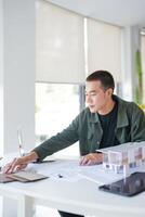 Architecture Man sitting at a table with model house photo