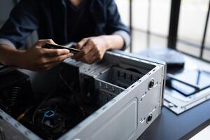 IT Engineer man is using a cell phone to check the status of his computer photo