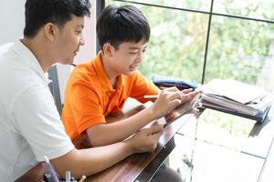 asian father and son working on homework together photo