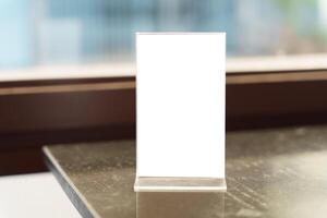 a blank white menu mockup on a table in front of a window photo