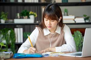 a student woman is sitting at a table with a laptop and a notebook. online learning class photo