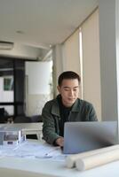 Architecture man sitting at a table with a laptop photo