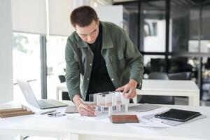 Architecture is working on a model of a house at office photo