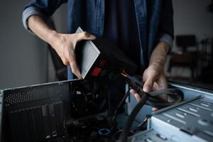 IT Engineer man is holding a computer and plugging it into a power supply photo