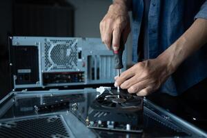 engineer is fixing a computer with a screwdriver photo