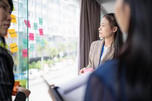 three businesswomen standing in front of a window with sticky notes on them photo