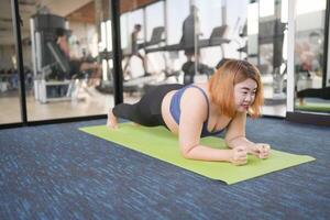 Overweight woman doing plank exercise in the gym photo