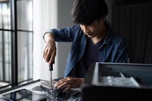 IT Engineer is working on a computer with a screwdriver photo