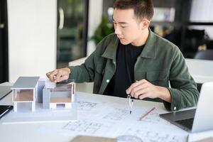 Architecture Man is working on a model of a house in office photo