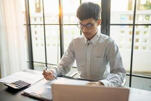 businessman signing or writing document paperwork and report Auditor analysis male professional hand making notes with Document. photo