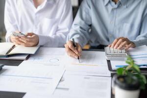 two people sitting at a table with papers and calculators photo