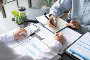 two people are working on a business document at a desk photo
