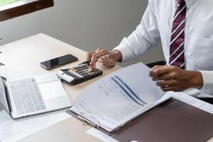 a man in a white shirt and rad tie is using a calculator photo