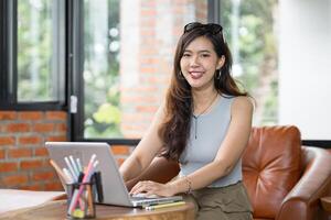 Portrait of Asian business female using laptop beautiful woman working on a computer in stylish Working Design in workplace. photo