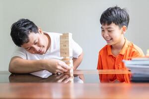 Asian father and son playing wood blocks game Carefree kid playing wood blocks game building constructor from blocks photo