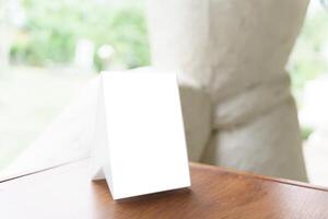 a white square menu on a table in front of a window photo