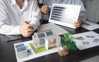 two engineers are holding a solar panel and a model of a house photo
