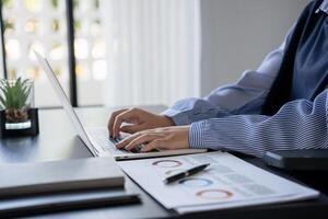 a person sitting at a desk using a laptop computer photo