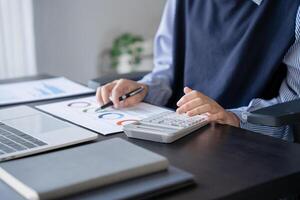 a person sitting at a desk with a laptop and a calculator photo