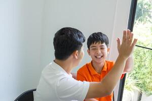 a man and a boy are sitting at a table doing hi five photo