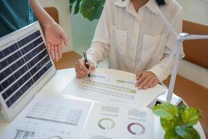 a woman is signing a document with a man and a wind turbine photo