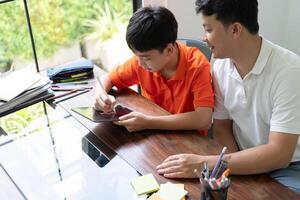 asian father and son using tablet computer at home photo
