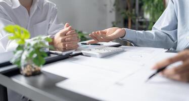 two people sitting at a table with papers and a calculator in office photo