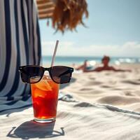 A glass of orange juice with sunglasses on the beach photo