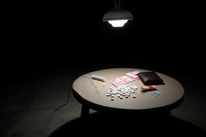 A table with pills, a lighter and a wallet photo