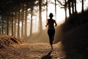 A woman running in the woods at sunrise photo