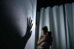 A shadow of a woman holding a baby in front of a curtain photo