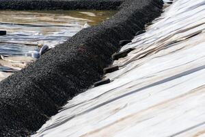 Erosion Control Structure with Aggregate and Used Tires for Slope Stabilization and Sediment Control on White Fabric photo