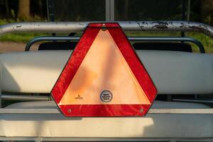 Close up of slow moving vehicle sign mounted to cart with red reflector border and a peach triangle center panel photo