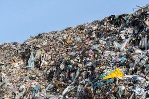 Overflowing landfill under sunny sky, showcasing waste accumulation, pollution problems, and environmental concerns on large refuse heap photo