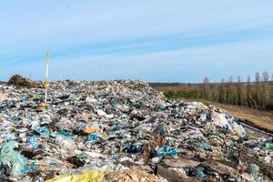 Vast landfill landscape with collected waste against open sky featuring a flock of birds, emphasizing environmental issues photo