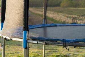 Trampoline with safety net and blue padding in backyard, providing recreational fun and bounce for children and family activities photo