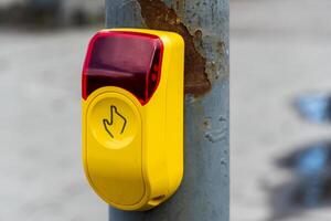 Pedestrian crosswalk signal button with hand symbol on weathered metal pole, yellow box with red light signaling safe crossing photo