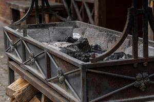 Rustic metal fire pit with burned logs and wood storage underneath displaying signs of age and weathered use. photo