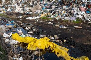 Large Landfill Polluting a Waterway, Overflowing with Discarded Plastics and Waste Materials, Causing Severe Environmental Damage photo