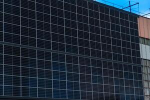 Array of Photovoltaic Cells Covering Exterior Wall for Sustainable Energy Generation with Cloudy Sky and Building Structure photo