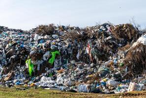 Overfilled rubbish heap with discarded plastic, waste material, and tree branches at landfill site posing environmental threat photo