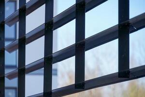 Rectangular framework of steel structure with bolts, horizontal lines, window reflection, outdoor grid construction. photo