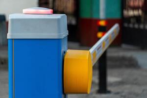 A traffic barrier stands at an entrance, featuring a red light signaling that access is restricted. The pole is raised, indicating the barrier is currently inactive photo