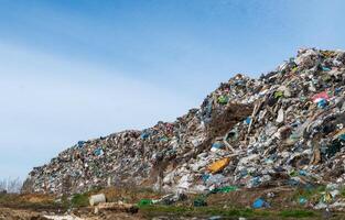 A large landfill showcases heaps of colorful plastic waste and debris under a clear blue sky, emphasizing pressing environmental concerns photo