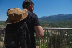Traveler Exploring Scenic Mountain Views with Backpack and Hat on a Sunny Day photo