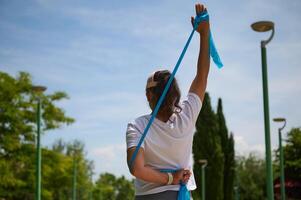 Rear View of a Woman Stretching Outdoors with Resistance Band on a Sunny Day photo