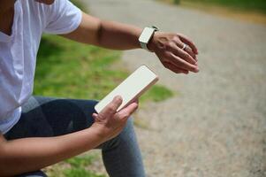 Active Woman Using Mobile Phone and Smartwatch Outdoors in a Sunny Park Setting photo