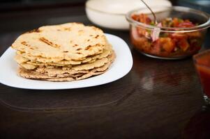 Plate of Freshly Made Tortillas and Salsa Displayed on a Wooden Table photo