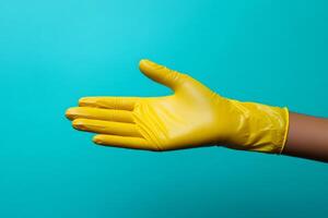 Hand with yellow cleaning glove making welcome gesture on a turquoise background photo