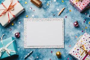 Christmas background with blank paper and gift boxes surrounded by colorful confetti photo